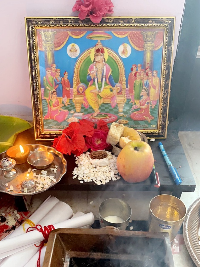 Chitragupta Puja at home: picture of Chitragupta ji with flowers, lamp, pens and rolled paper